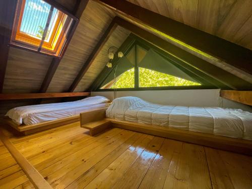 Cette chambre comprend deux lits et une fenêtre mansardée. dans l'établissement Vila Davidovic-Fruska gora, à Manđelos