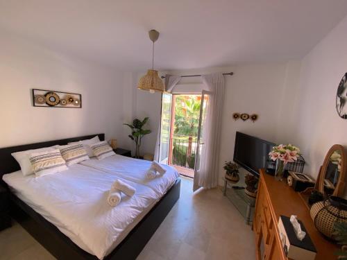 Cette chambre comprend un lit avec des draps blancs et une télévision. dans l'établissement Spacious and stylish penthouse in Mijas, à Mijas