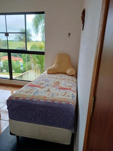 a small bed in a room with a window at Casa Lot Fechado, Churrasqueira, Piscina, Toboágua, parque para crianças , Internet in Piracaia
