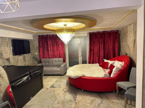 ein Schlafzimmer mit einem großen roten Bett und einem Sofa in der Unterkunft Golden Love - Jacuzzi in Rouen