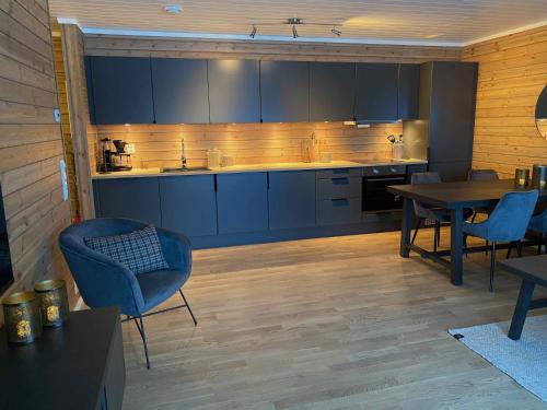cocina con armarios azules, mesa y sillas en New modern apartment with great view - ski in & out, en Skulestadmo
