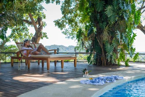 una mujer sentada en una silla junto a una piscina en Tierra Magnifica Boutique Hotel, en Nosara