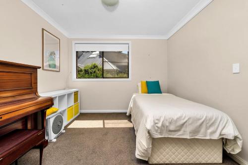 a small bedroom with a bed and a piano at Breakers on Orion Beach Vincentia in Vincentia
