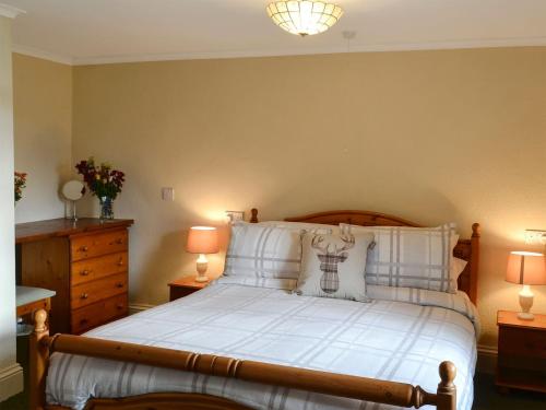 a bedroom with a bed with white sheets and two lamps at Buckswell Cottage in Hury