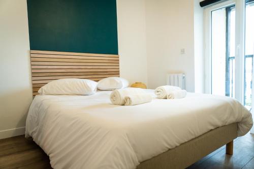 um quarto com uma grande cama branca com toalhas em Magnifique T2 centre ville dernier étage avec balcon em Valence