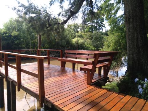 a wooden deck with a bench next to a tree at Delta Tigre in Tigre