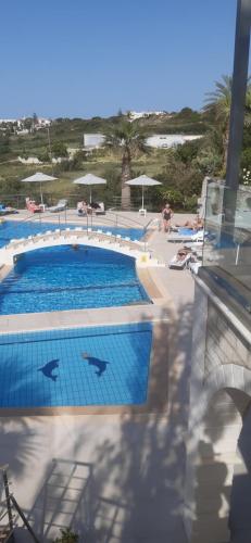 a swimming pool at the beach with umbrellas at Oasis Scaleta Hotel in Skaleta
