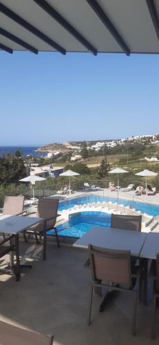 a patio with tables and chairs and a swimming pool at Oasis Scaleta Hotel in Skaleta