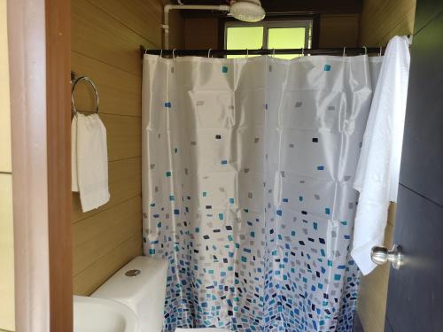 a bathroom with a white shower curtain and a toilet at Glamping Tiny house 