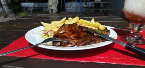 une assiette de viande et de frites sur une table avec une boisson dans l'établissement Masingitana Greater Kruger Safaris, à Utlha