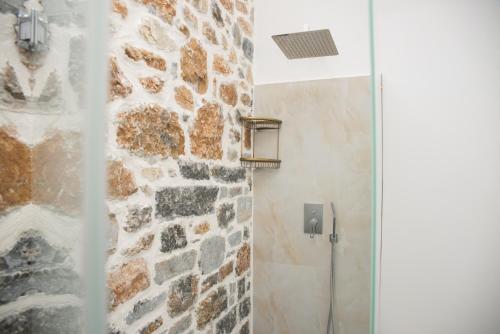 a bathroom with a walk in shower next to a stone wall at Luxury Villa Saint Nikolas in Voskopojë