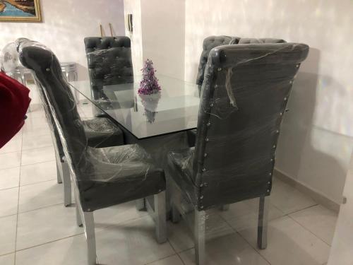 a glass table with three black chairs and a glass table with a christmas tree at Residencial sarah de los Angeles in SJM