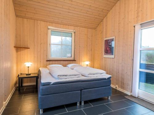 ein Schlafzimmer mit einem Bett in einem Zimmer mit Holzwänden in der Unterkunft Holiday home Fanø CLXXXVI in Fanø