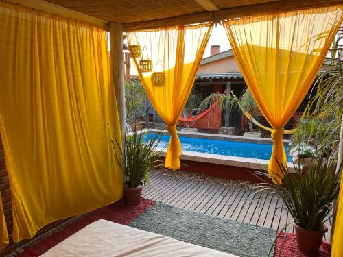un patio con cortinas y plantas amarillas y una piscina en PAZ Y ARMONÍA en chuy 2, en Chuy