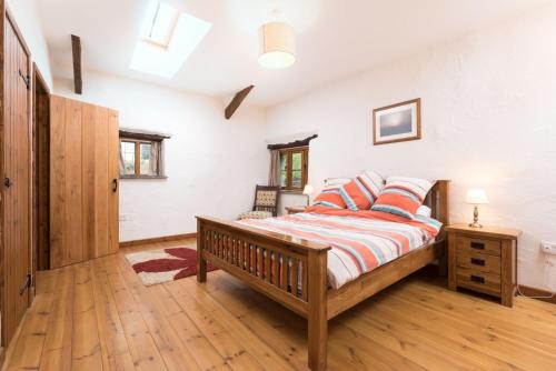 um quarto com uma cama e piso em madeira em The Byre em Goodleigh
