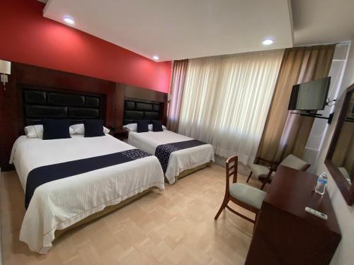 una camera d'albergo con due letti e una televisione di HOTEL IMPALA DE TAMPICO a Tampico