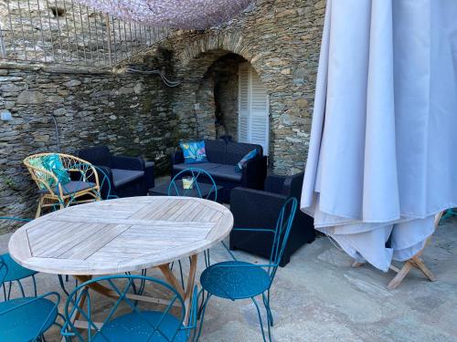 a table and chairs in a patio with a stone wall at Torra di Ciocce in Pino