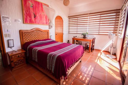 a bedroom with a bed and a table and a window at Hotel boutique Teocalli in Tepoztlán