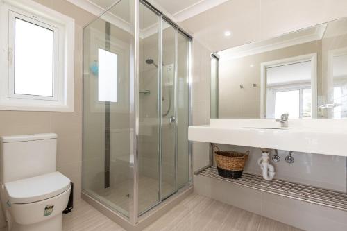 a bathroom with a shower and a toilet and a sink at King George Parade in Forster