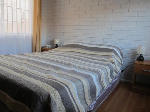 Una cama con una manta a rayas en un dormitorio en Casa Independiente Serena Oriente, en Coquimbo