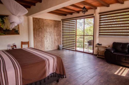 a bedroom with a bed and a couch and windows at Hotel boutique Teocalli in Tepoztlán