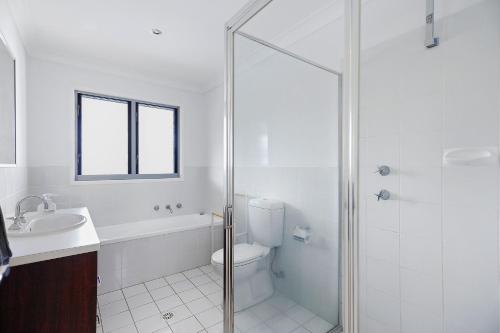 een badkamer met een douche, een toilet en een wastafel bij Coastal Cove Huskisson in Huskisson