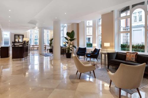 un hall avec des chaises et des canapés dans un bâtiment dans l'établissement Radisson Blu Kenilworth Hotel, London, à Londres