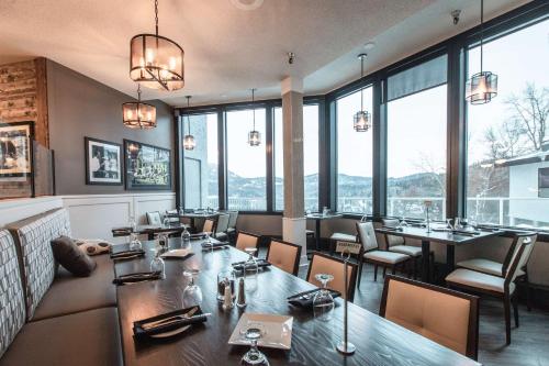 a restaurant with tables and chairs and large windows at Prestige Mountain Resort Rossland in Rossland