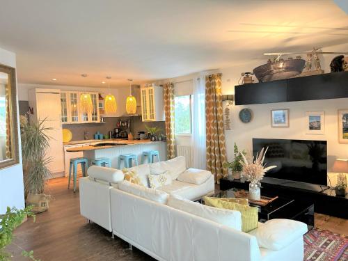 a living room with a white couch and a kitchen at Surf ou Golf House a quelques pas de l'océan in Moliets-et-Maa