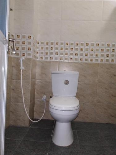 a white toilet in a bathroom with a hose at Jayathmaguest in Peradeniya