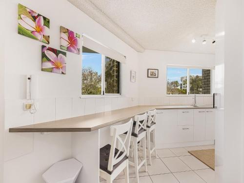a kitchen with white cabinets and a counter with stools at Nelson Point Unit 2 Golden Beach QLD in Golden Beach
