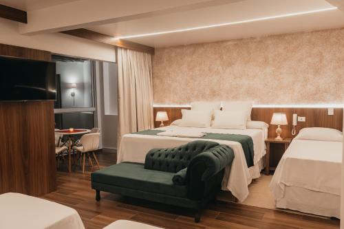 una camera d'albergo con due letti e un divano di Hotel Cabana Suiça a Guaratuba