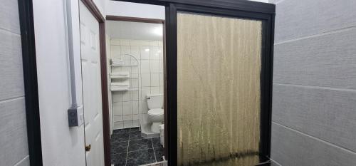 ein Badezimmer mit einem WC und einer Glastür in der Unterkunft Sleep&Go! Family room - Cabina empresarial en Siquirres in Siquirres
