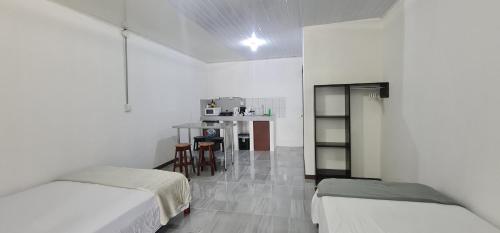 a white room with two beds and a table at Sleep&Go! Family room - Cabina empresarial en Siquirres in Siquirres