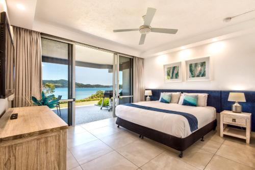 a bedroom with a bed and a view of the ocean at Beach Lodges in Hamilton Island