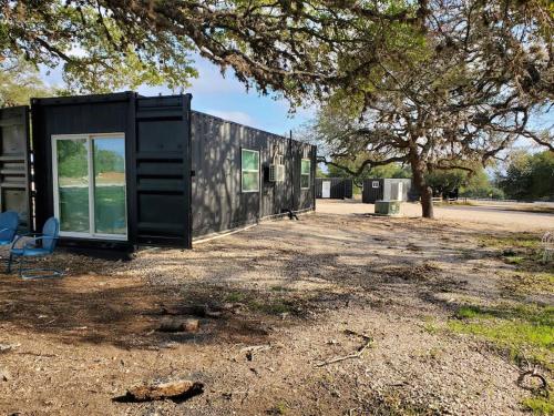 a black tiny house sitting on the ground under a tree at TCR at 290 Wine Trail #13 Now dog friendly in Hye