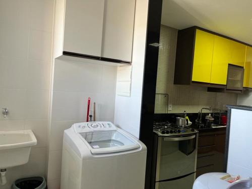 eine kleine Küche mit einem Herd und gelben Schränken in der Unterkunft apartamento praia do morro - beira mar in Guarapari