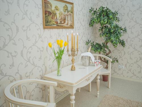 einen Tisch mit einer Vase aus Blumen und zwei Stühlen in der Unterkunft Luxury Apartments with Jacuzzi in Sumy