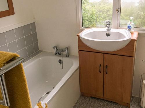 a bathroom with a sink and a bath tub at Siskin Lodge - Uk39664 in Lunga