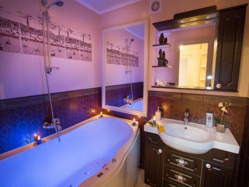ein Bad mit einer Badewanne und einem Waschbecken mit Beleuchtung in der Unterkunft Luxury Apartments with Jacuzzi in Sumy