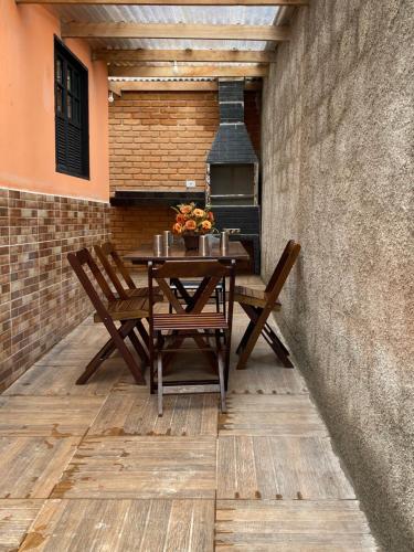 une table et des chaises sur une terrasse avec une cheminée dans l'établissement Chalé Flor da Serra, à Conceição da Ibitipoca