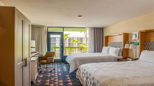 メサにあるHoliday Inn & Suites Phoenix-Mesa-Chandler, an IHG Hotelのベッド2台とバルコニーが備わるホテルルームです。