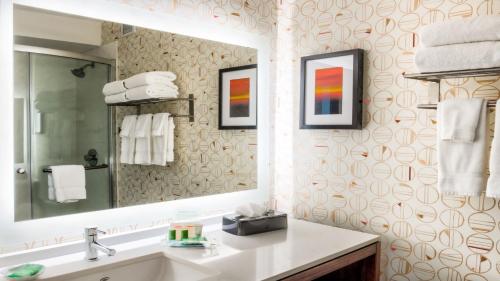 a bathroom with a sink and a mirror and towels at Holiday Inn & Suites Phoenix-Mesa-Chandler, an IHG Hotel in Mesa