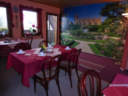 ein Esszimmer mit rosa Tischen und Stühlen sowie einem Gemälde in der Unterkunft An der Uferpromenade in Worbis