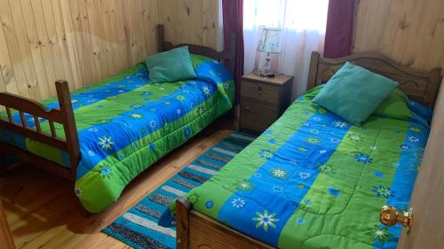 dos camas sentadas una al lado de la otra en un dormitorio en Cabañas Rukafun 1, en Pucón