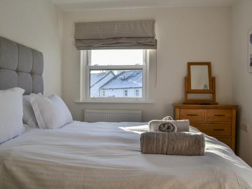 a bedroom with a white bed with a towel on it at Derwent Cottage in Keswick