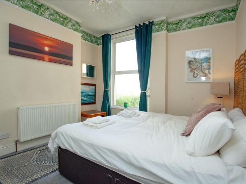 a bedroom with a large white bed with a window at Devon Beach Station in Paignton
