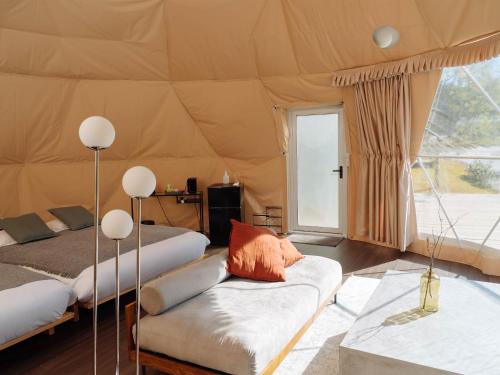 pokój z 2 łóżkami i kanapą w namiocie w obiekcie BAMBOO RESORT MIHAMA　繋 w mieście Mihama