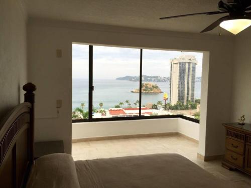 a bedroom with a large window with a view of the ocean at Departamento Familiar en Acapulco con Hermosa Vista! in Acapulco