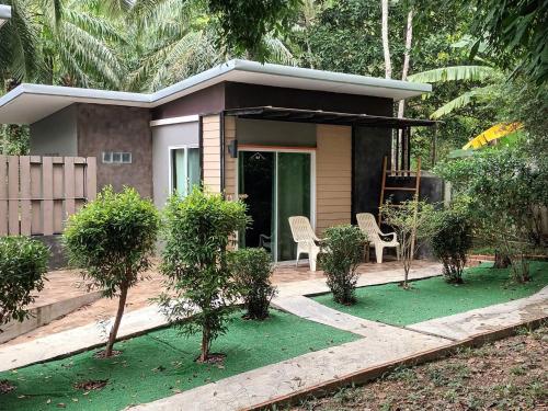 uma pequena casa com cadeiras e árvores em frente em BaanPhong Lanta em Ko Lanta